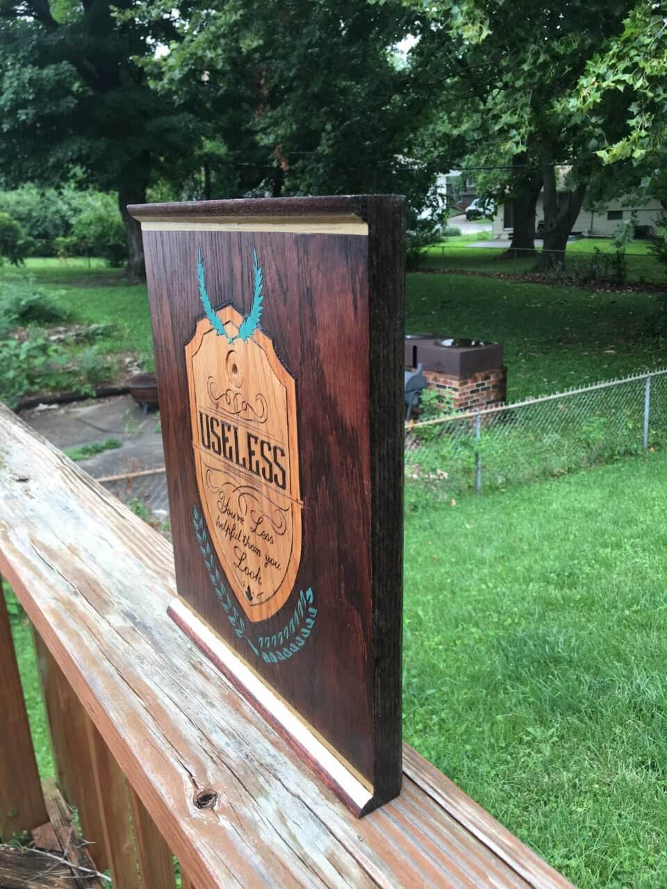 Useless Plaque - a pyrographic piece of oak wood that is stained, and painted with metallic paint and coated with protectant